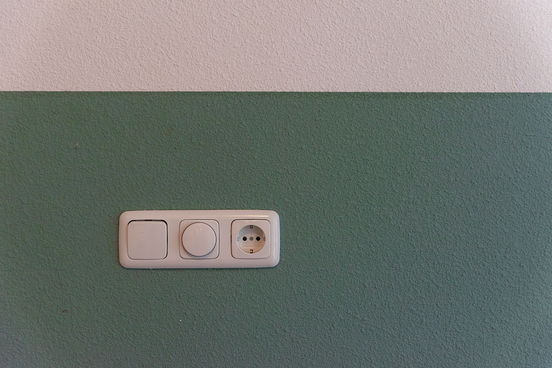 Prise et interrupteur posés sur un mur vert