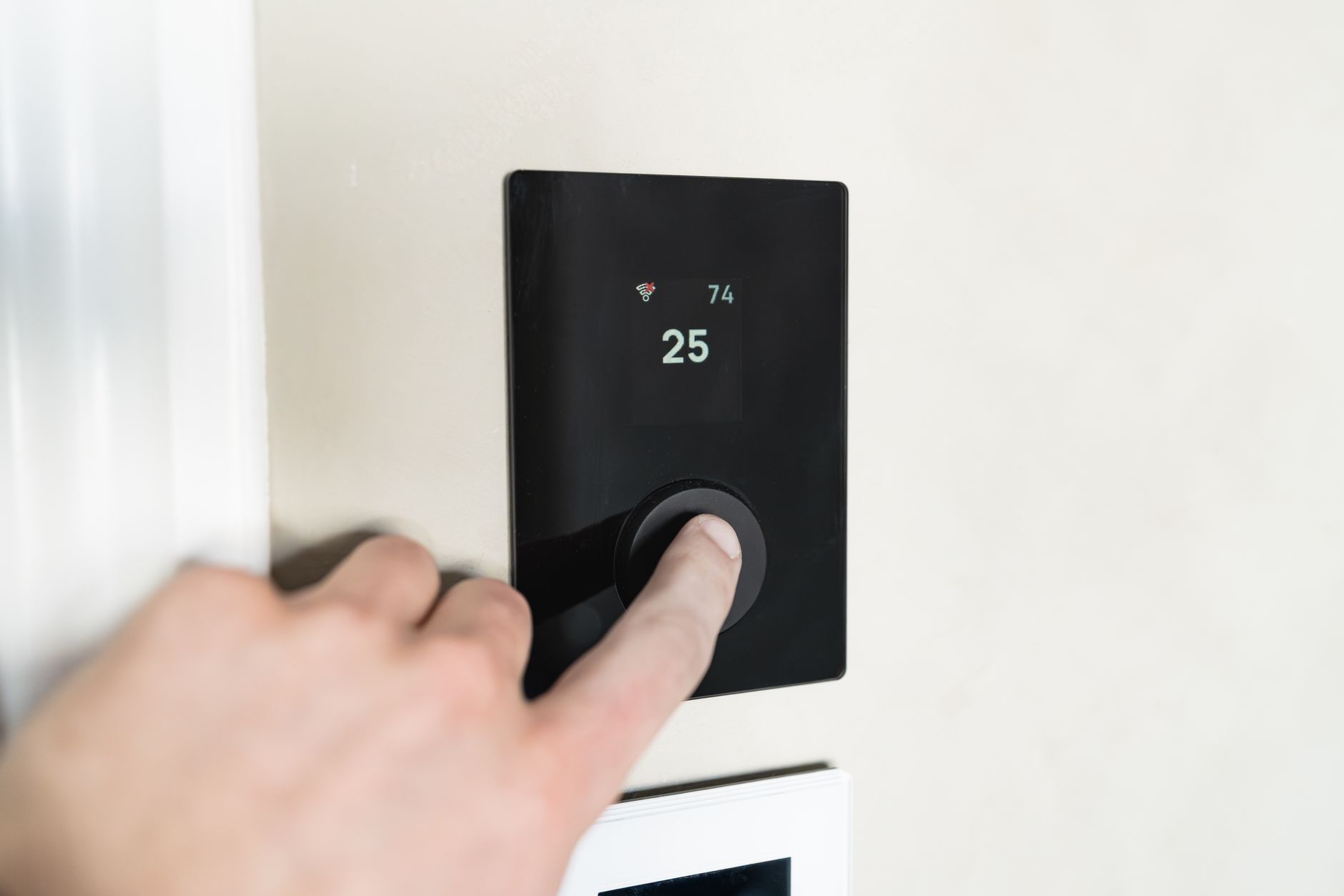 Main réglant un thermostat connecté